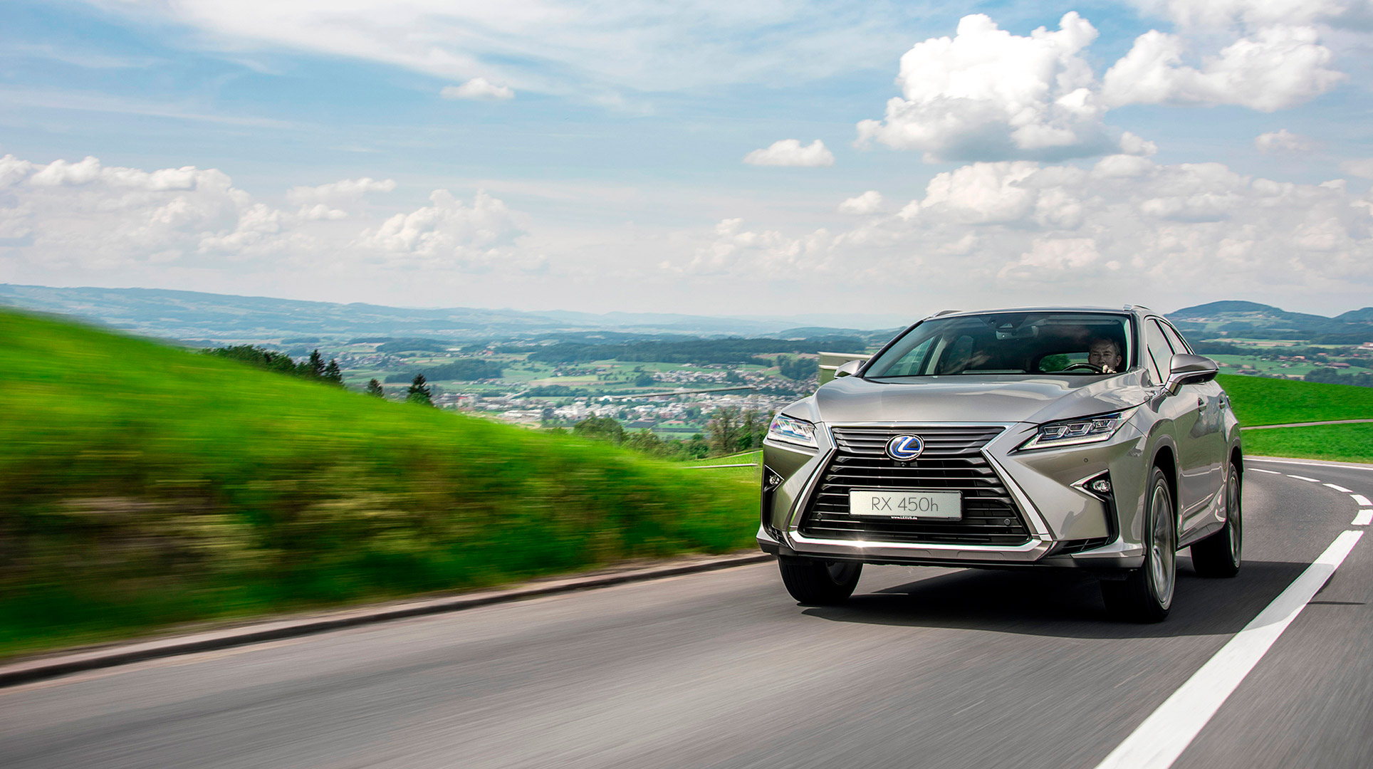 Vista frontal del Lexus RX 450h en una carretera con el cielo azul de fondo