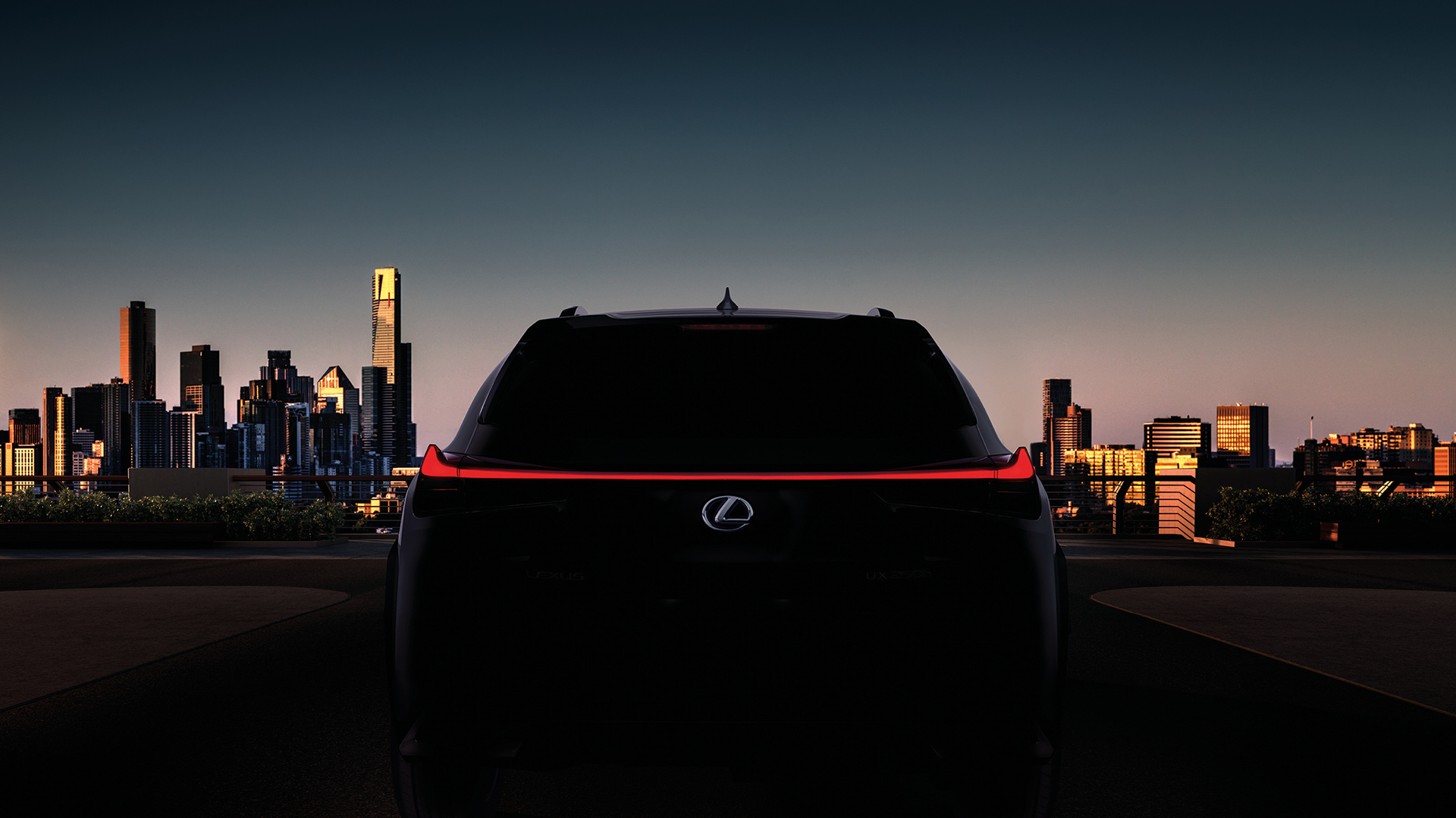 Vista trasera del Lexus UX250h con una ciudad de fondo