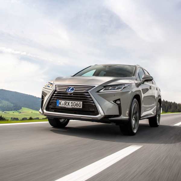 Vista frontal del Lexus RX 450h en una carretera con el cielo azul de fondo